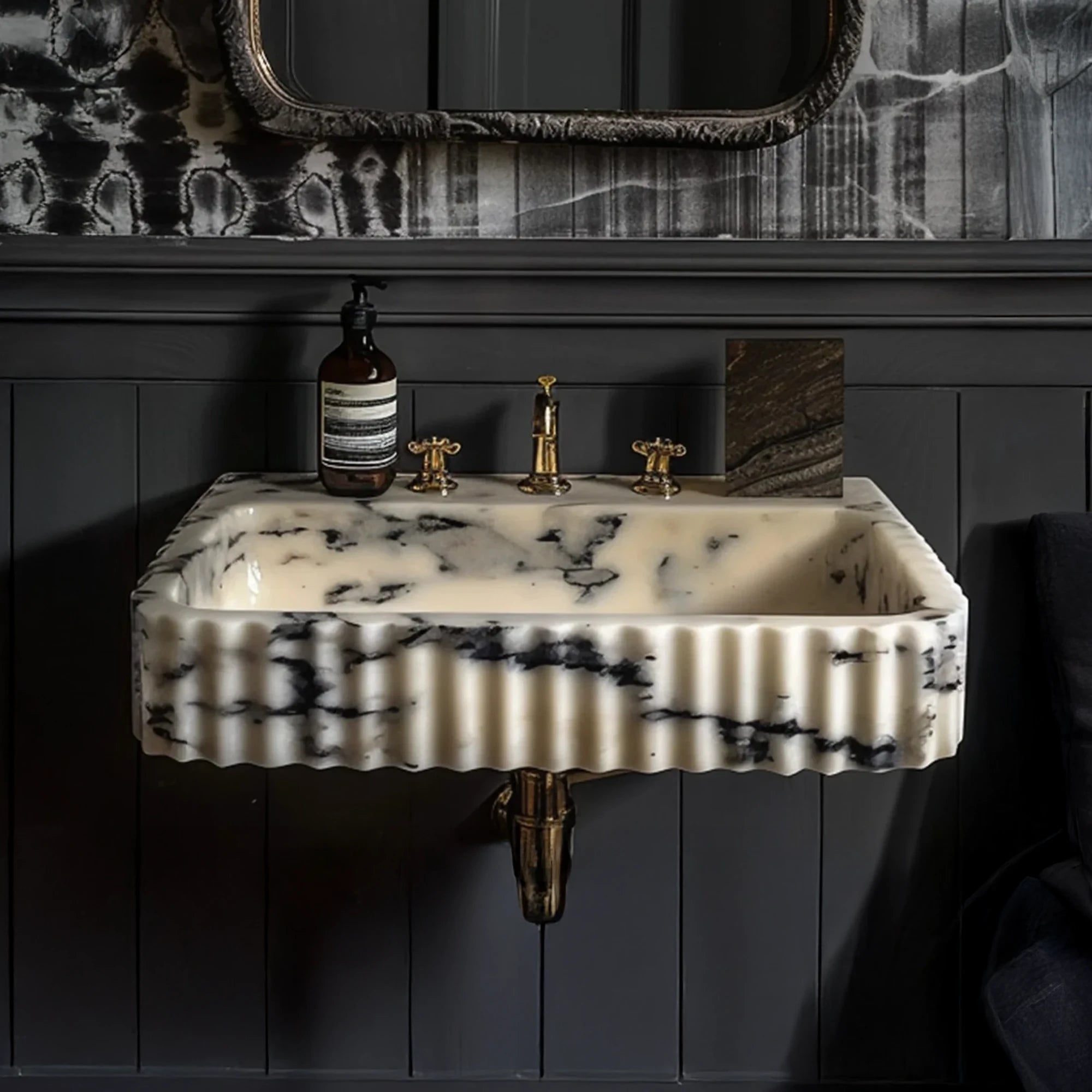 Wall mounted Calacatta Viola marble sink featuring deep black veining and elegant fluted carving, installed with brass hardware for a sophisticated bathroom look.